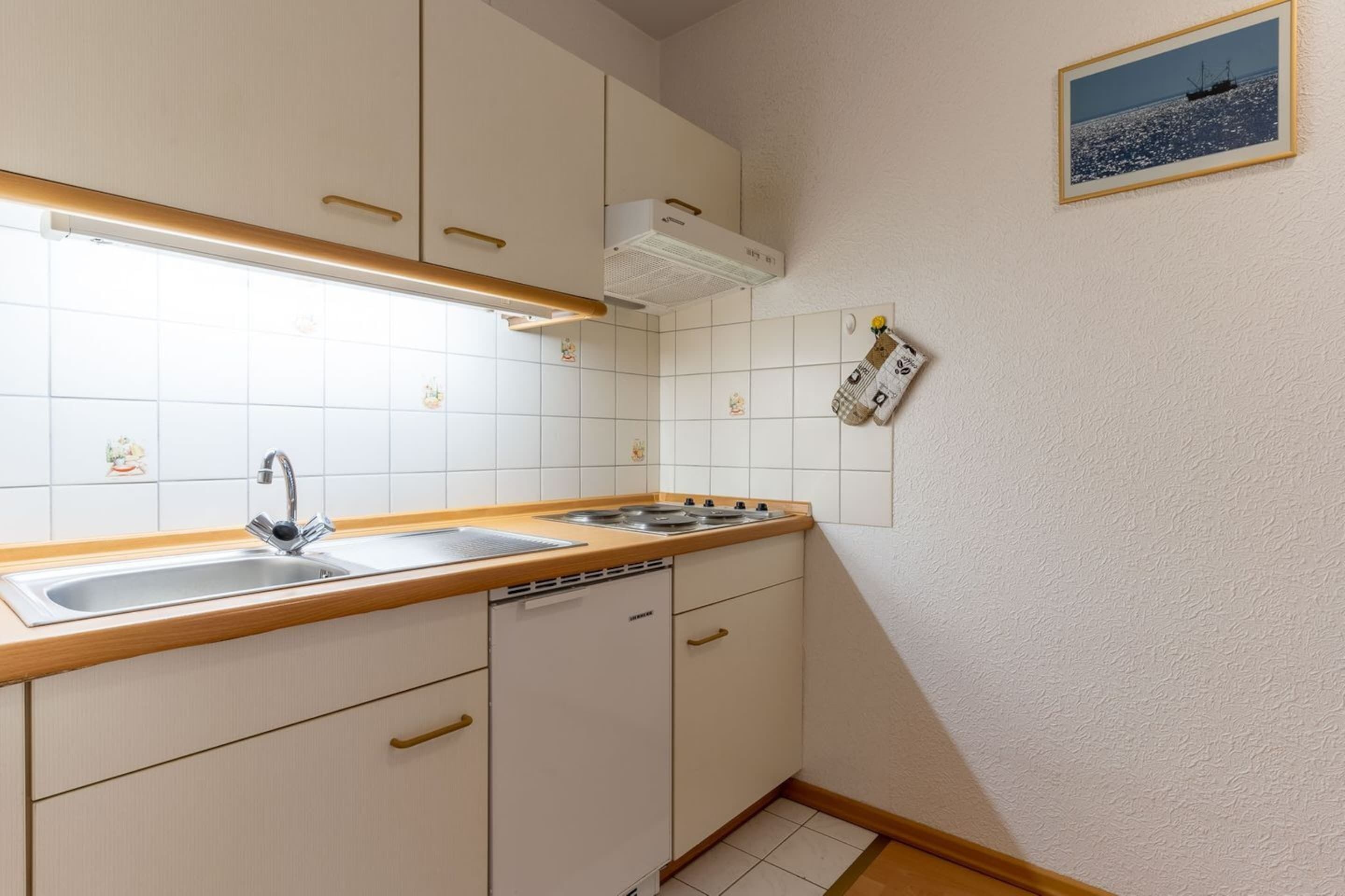 A compact kitchen with white cabinets, a double sink, and a built-in dishwasher.