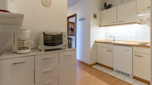 Keittiössä on valkoiset kaapit, kahvinkeitin, mikroaaltouuni ja astianpesukone.