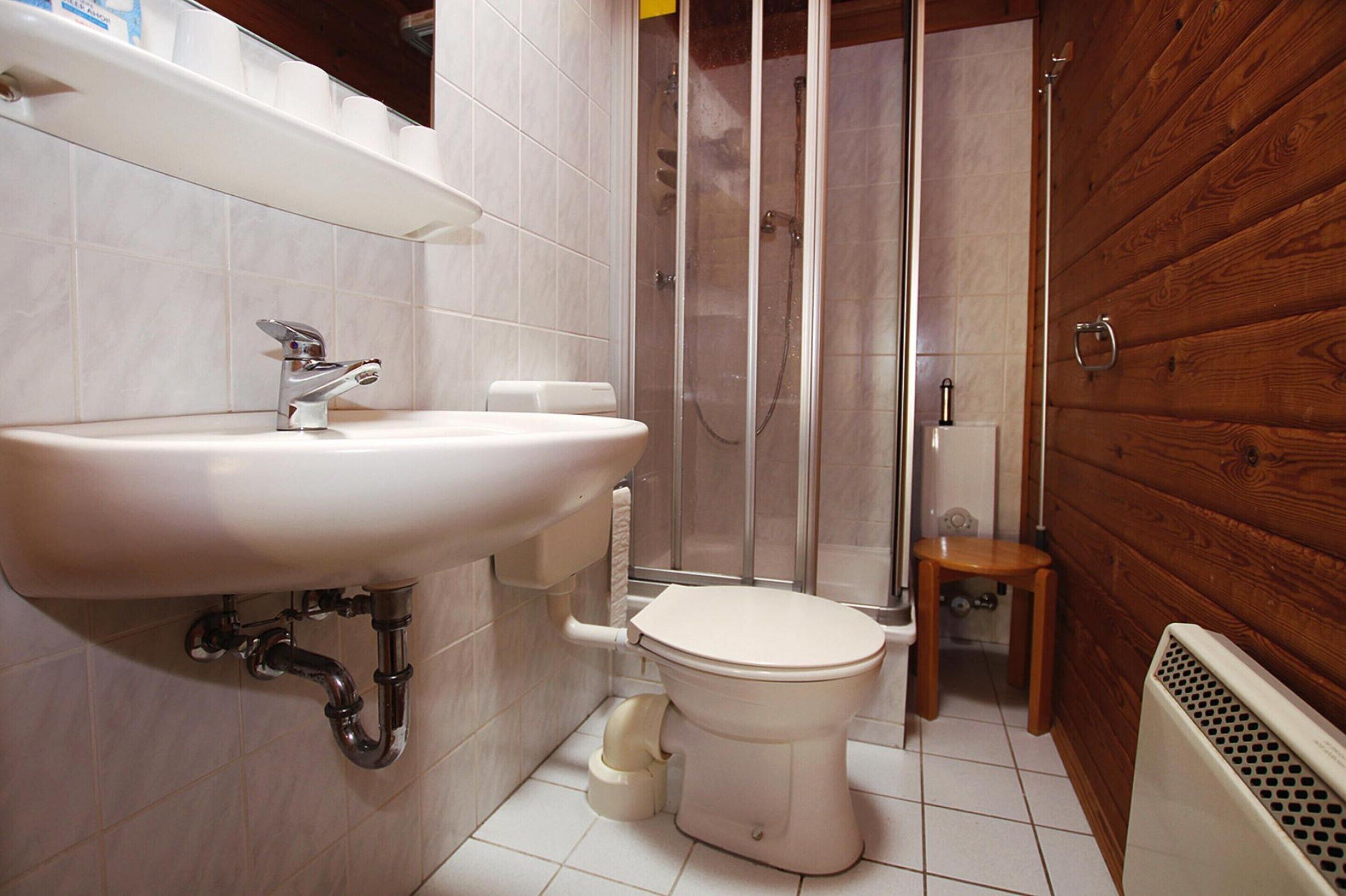 Une salle de bain équipée d’un lavabo, de toilettes, d’une douche et d’un lambris en bois.