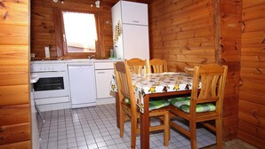 A wooden cabin kitchen with a dining table, chairs, a refrigerator, a sink, and a window. - Blockhaus, Hasselfelde (Oberharz am Brocken)