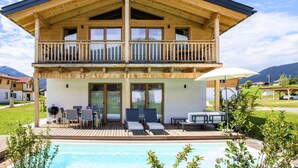 A two-story wooden chalet with a balcony, a pool, and outdoor seating. - Bergchalet Falkenstein, Inzell (Inzell)