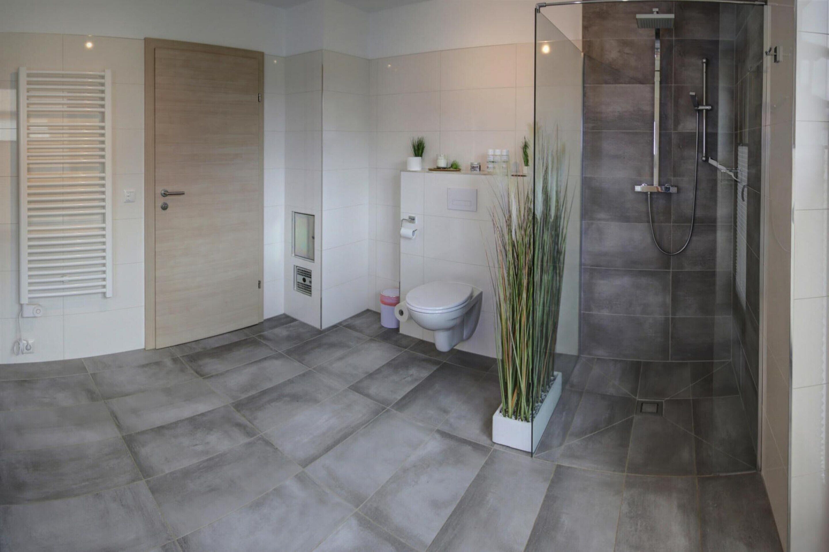 Un baño moderno con ducha, inodoro y un espejo grande.
