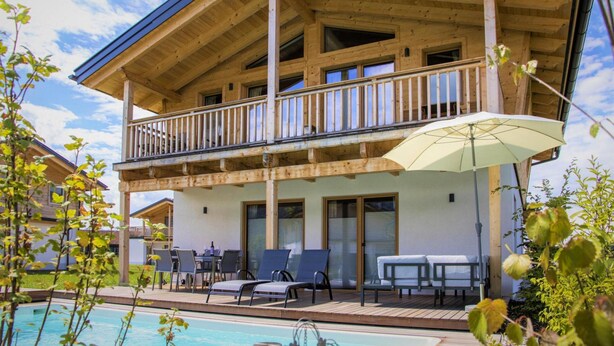 A wooden chalet with a balcony, outdoor seating, and a pool. - Bergchalet Falkenstein, Inzell (Inzell)