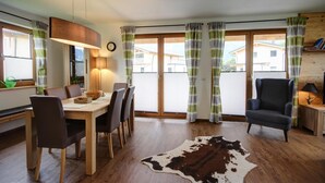 A dining area with a wooden table and chairs, a cowhide rug, and a chair with a lamp. - Bergchalet Falkenstein, Inzell (Inzell)