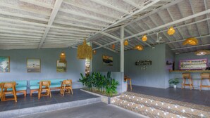 A spacious lobby with a high ceiling, wooden seating, a small indoor garden, and a bar area. - La Rise Penida Cottage (Penida Island)
