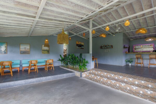 A spacious lobby with a high ceiling, wooden seating, a small indoor garden, and a bar area. - La Rise Penida Cottage (Penida Island)