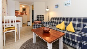 Un salon chaleureux avec un canapé à carreaux, une table en bois et une chaise blanche.