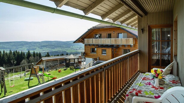 Een houten chalet met een balkon met uitzicht op een bergachtig landschap.