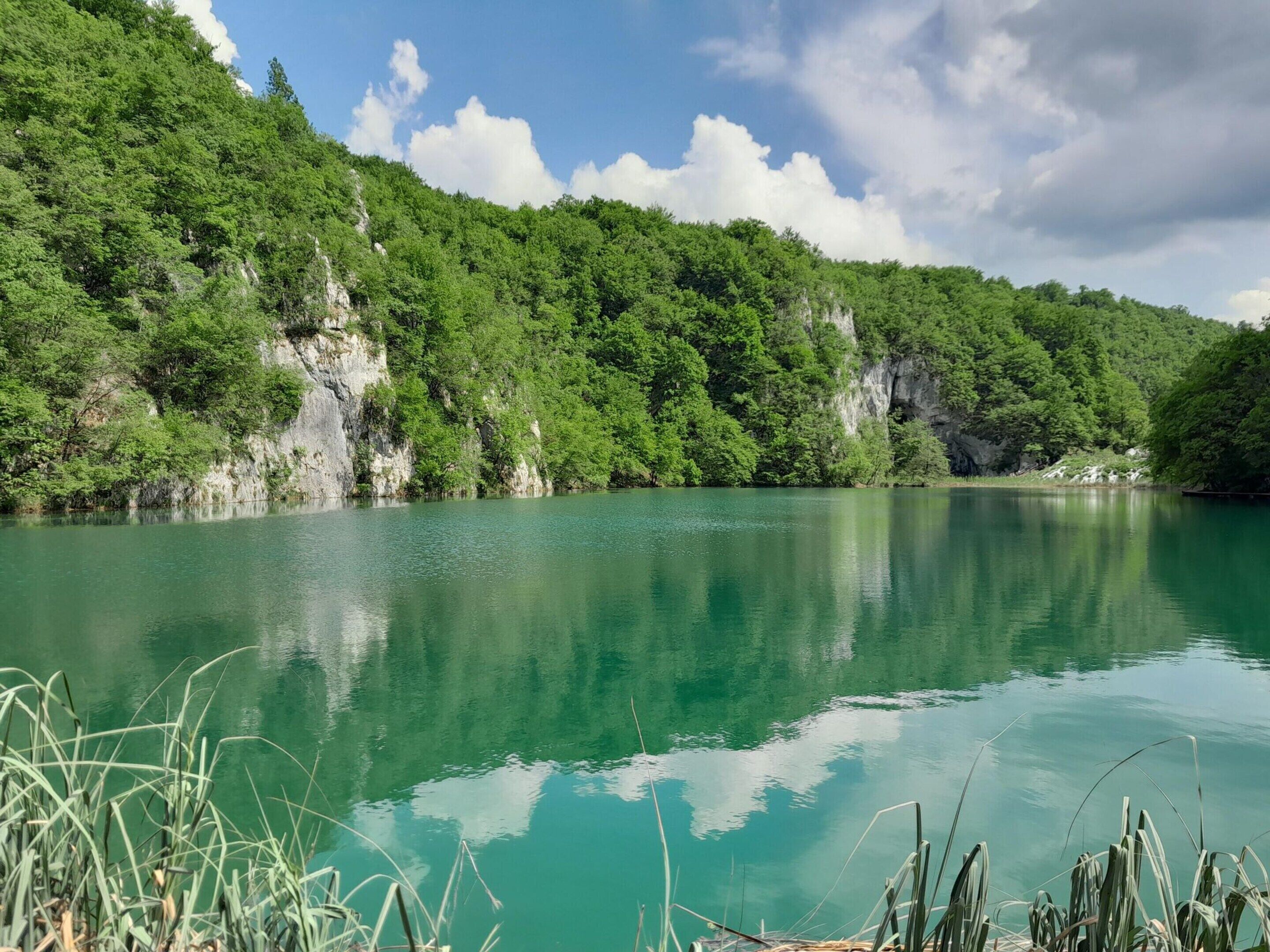A calm lake surrounded by lush green hills and cliffs.