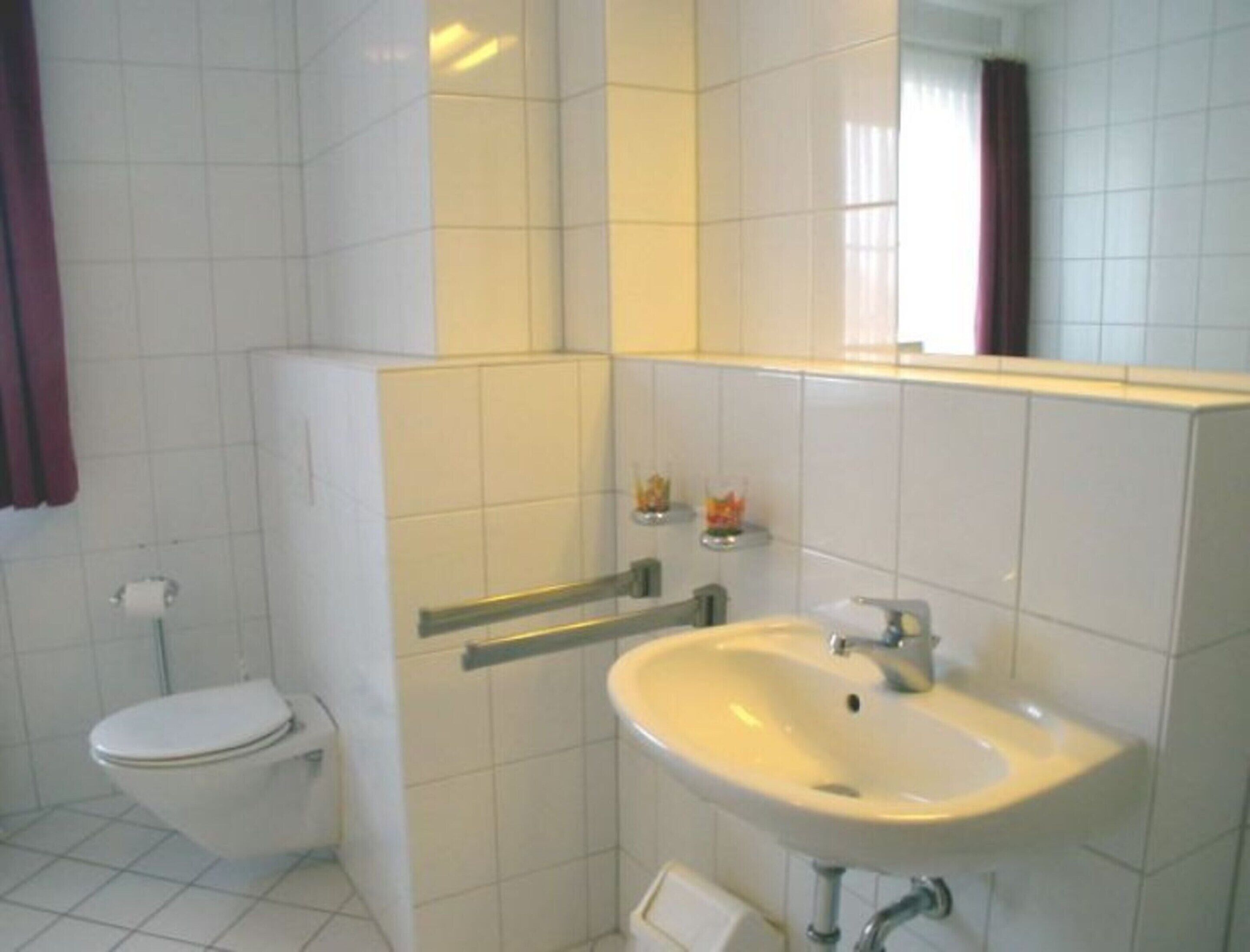 A bathroom with a toilet, a sink, and a mirror.