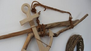 A wooden anchor and rope tied to a branch, with a starfish decoration.