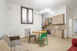 Ein kompakter Wohnraum mit Küchenzeile, einem Essbereich mit rundem Tisch und Stühlen sowie einer Couch.
