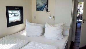 Ein Hotelzimmer mit Bett, Fenster, einem Gemälde und einer Tür zu einem Korridor.