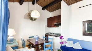 Una stanza accogliente con tavolo da pranzo, sedie, divano e angolo cottura.