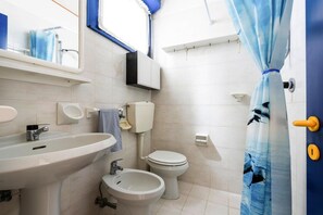 Un baño con lavabo, bidé, inodoro y cortina de ducha.