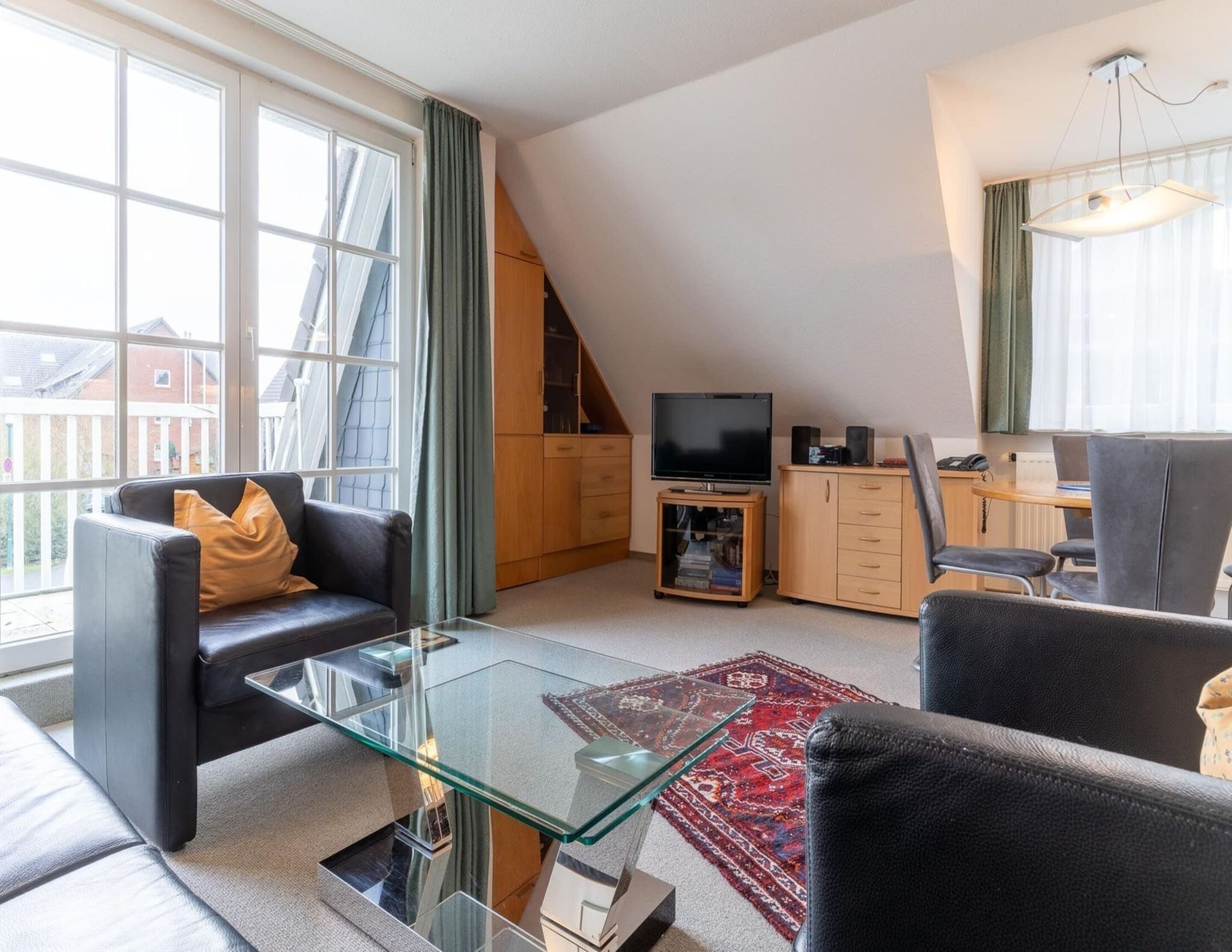 A modern living room with a glass coffee table, leather sofa, and a TV.