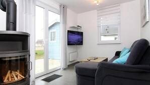 A modern living room with a fireplace, a sofa, a television, and a window with blinds.