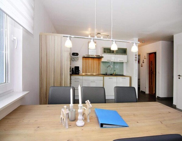 A modern kitchen with white cabinets, a wooden countertop, and a hanging light fixture. - Ferienhaus de Poeler Drift, Zierow (Zierow)