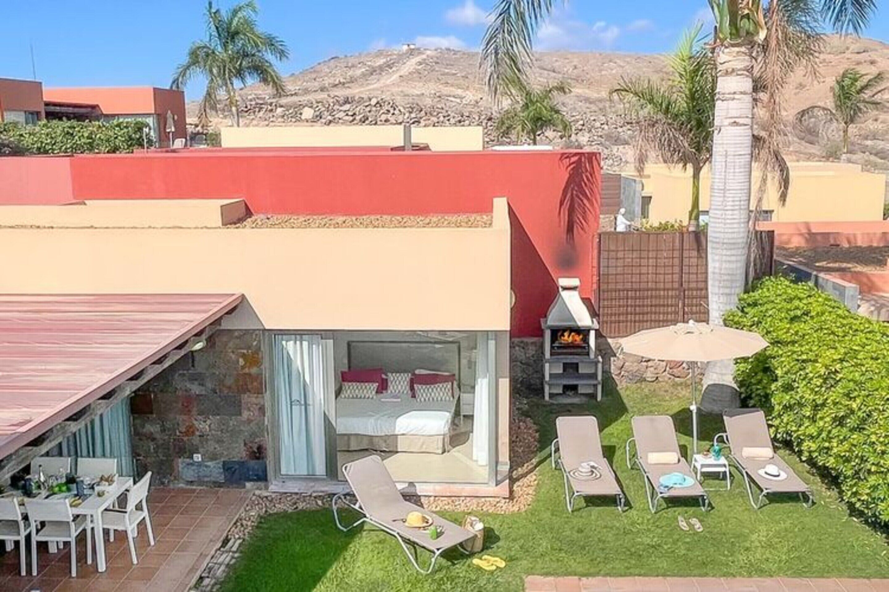 Un patio moderno al aire libre con zona de comedor, sillones de descanso y una parrilla.
