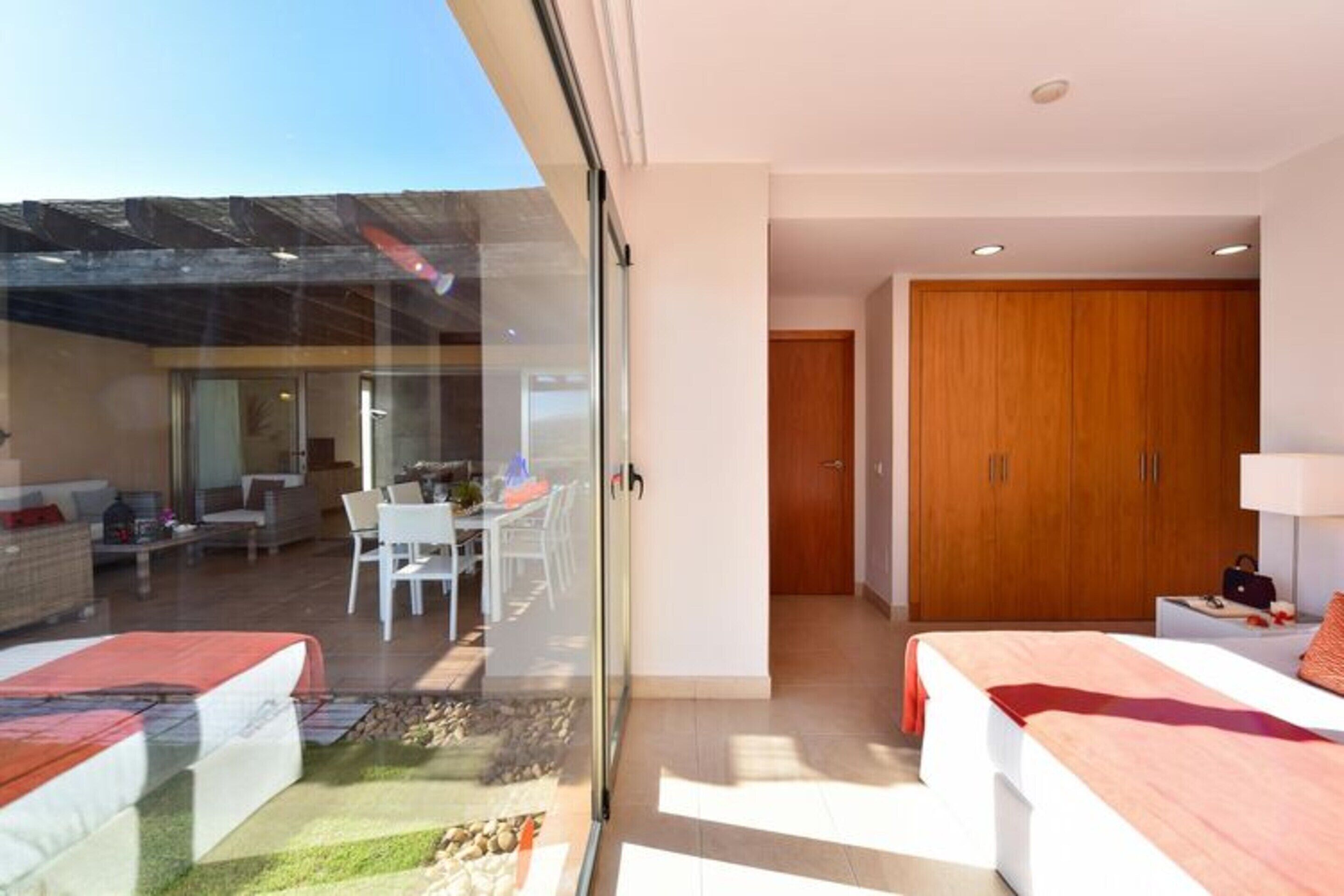 A modern hotel room with a glass wall, a balcony, and a wooden wardrobe.