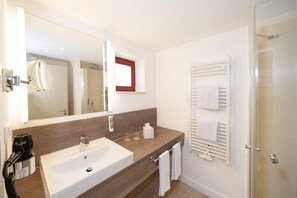 A modern bathroom with a large mirror, a sink, and a shower area. - Appartement am Plauer See in Ganzlin (Ganzlin)
