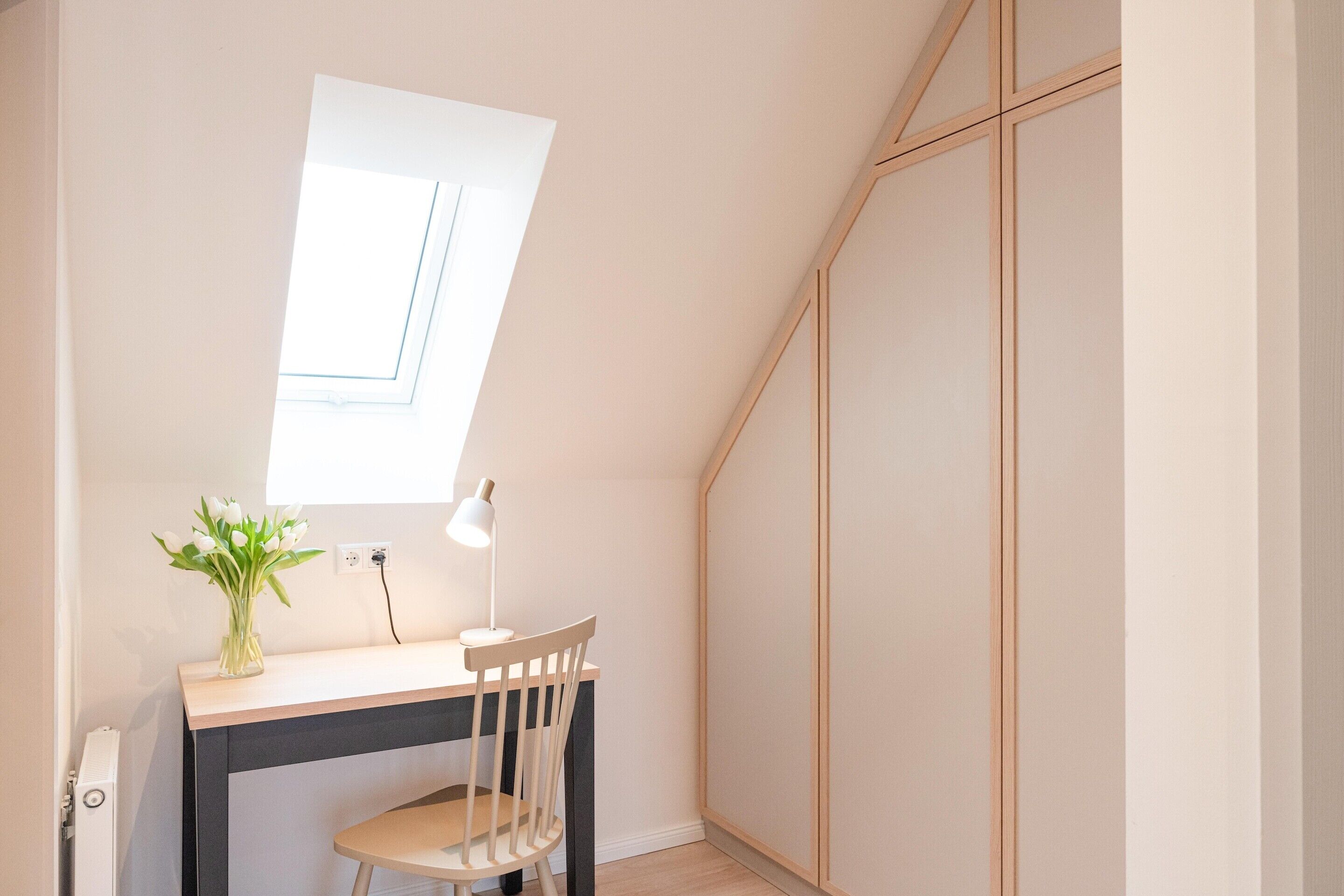 Una habitación pequeña y luminosa, con escritorio, silla y ventana.