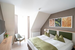 A modern hotel room with a bed, a desk, a chair, and a window with curtains. - Appartement am Plauer See in Ganzlin (Ganzlin)