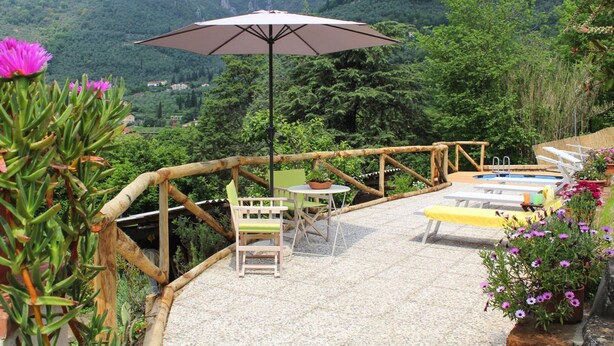 Un patio con mobiliario exterior, una piscina y vistas a un paisaje montañoso.