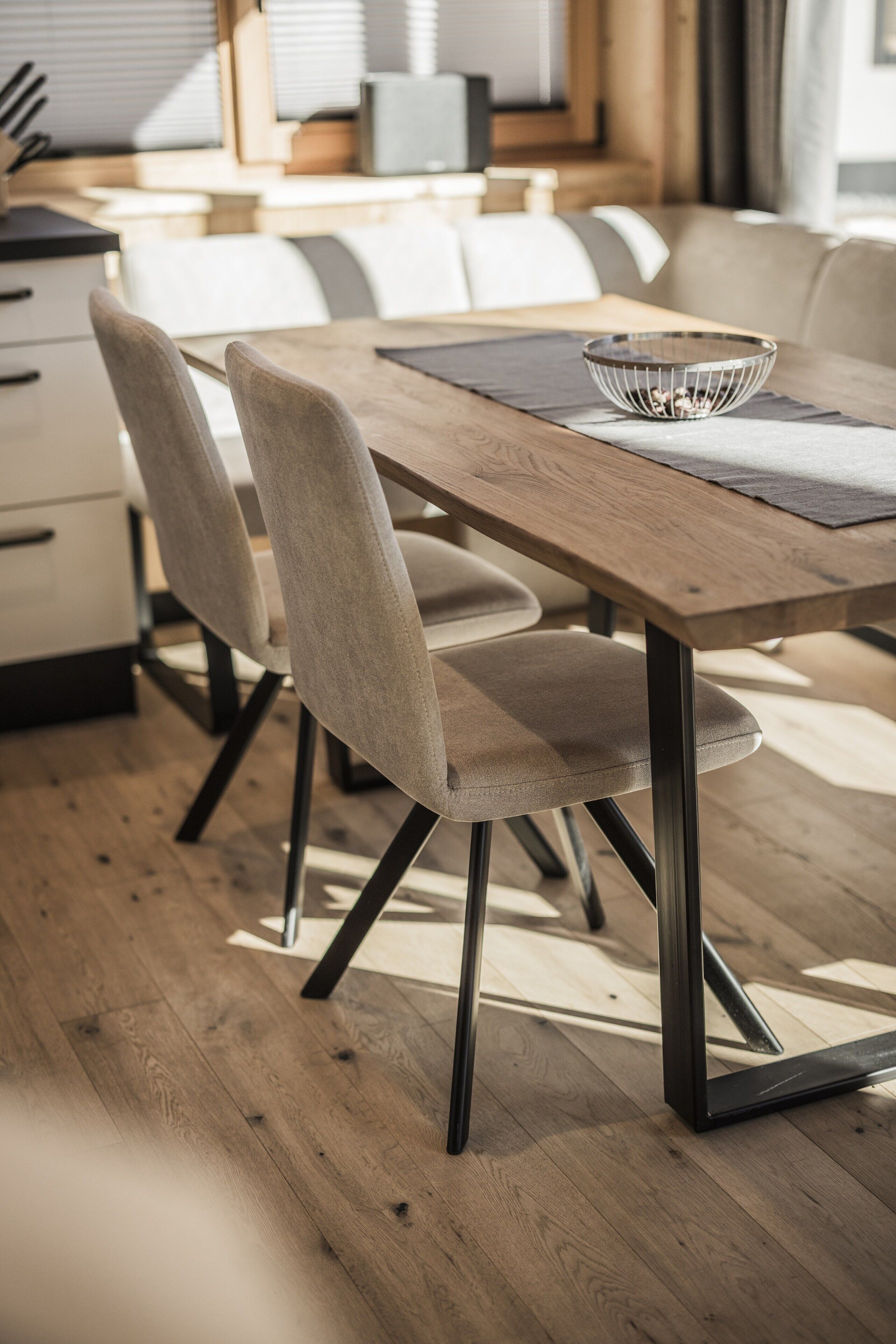 Ein moderner Essbereich mit einem Holztisch, gepolsterten Stühlen und einer Schüssel auf dem Tisch.