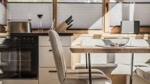 Une cuisine moderne avec des meubles en bois, une cuisinière en acier inoxydable et un coin repas comprenant une table et des chaises blanches.