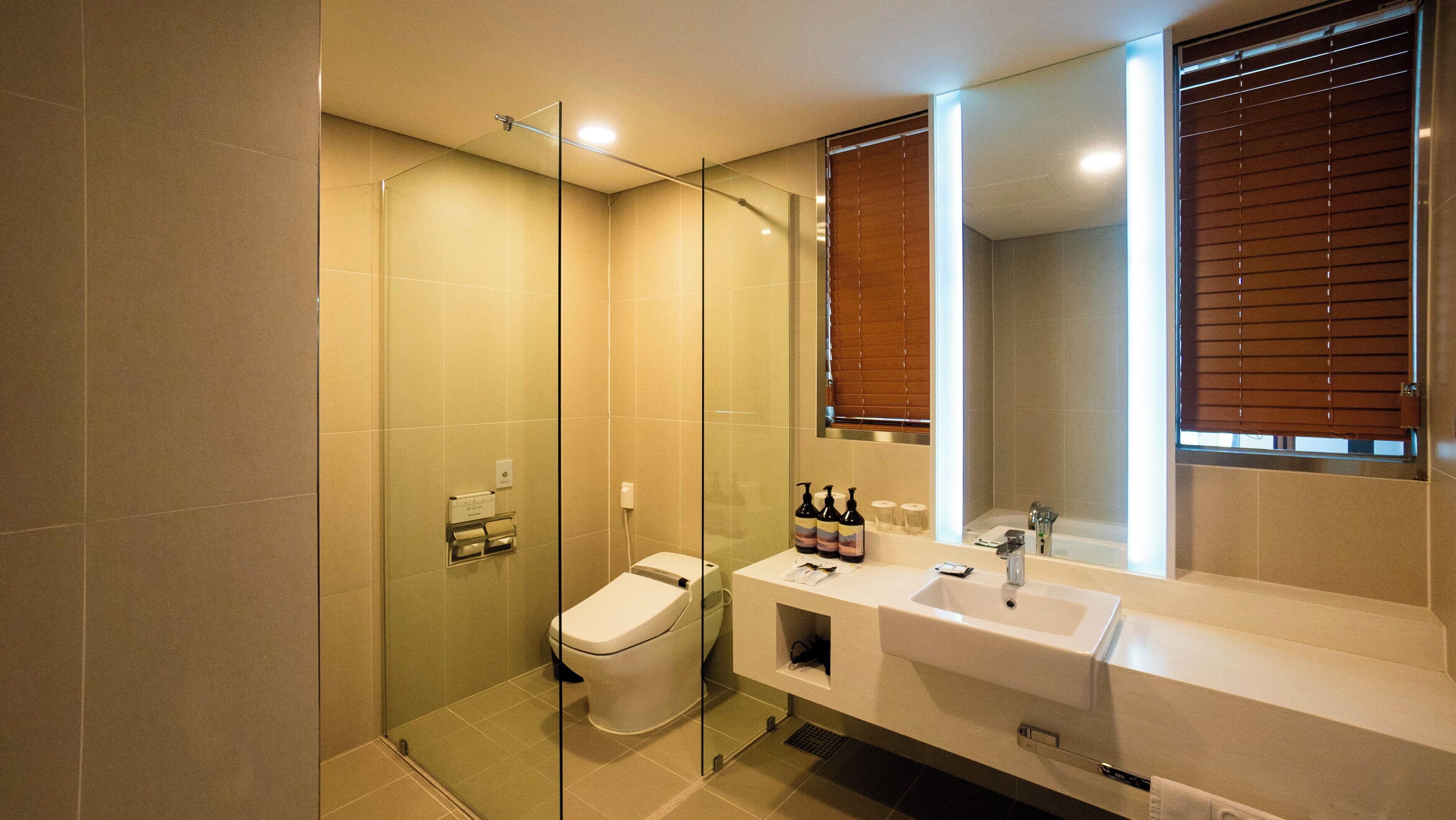 A modern bathroom with a glass-enclosed shower, a toilet, and a vanity with a mirror.