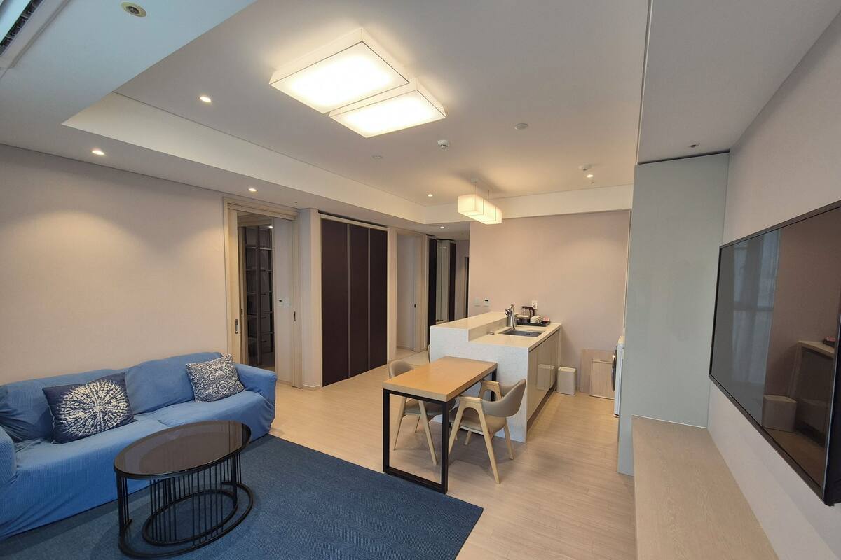 A modern living room with a sofa, coffee table, and a dining area with a table and chairs.
