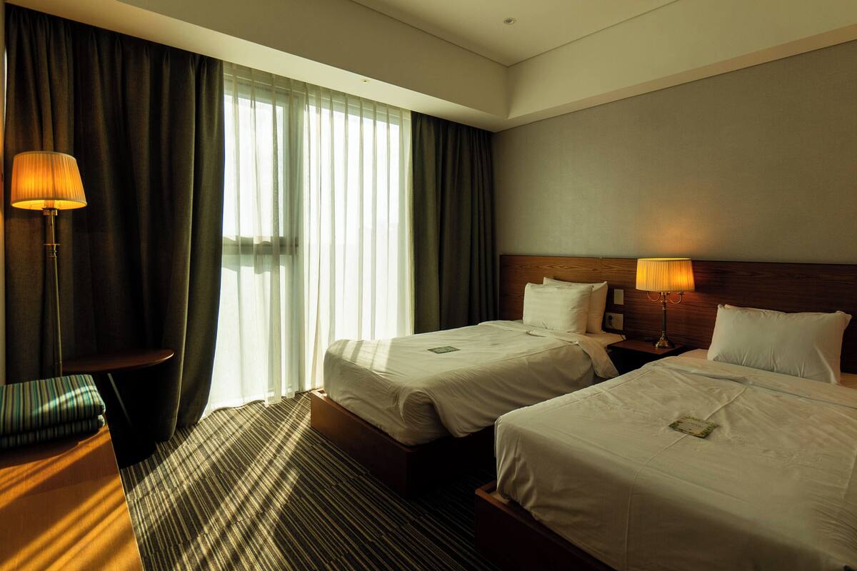 A hotel room with two beds, a desk, and a chair.