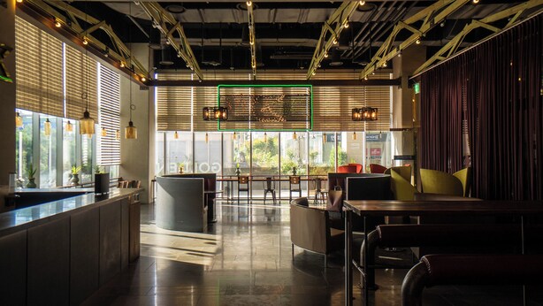 Interior de restaurant modern amb una barra central, zona de seients i grans finestres.