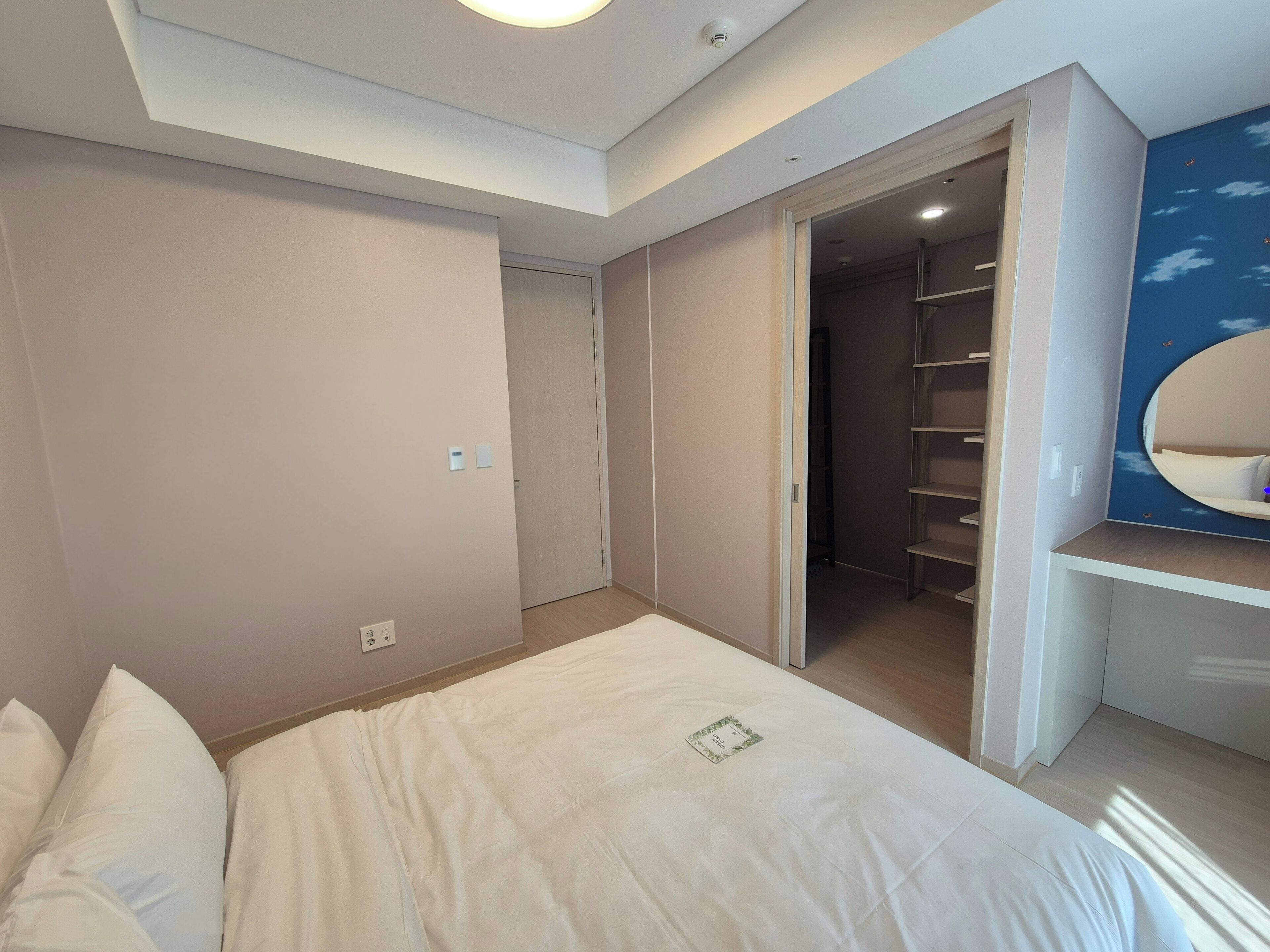 A bedroom with a bed, a closet, and a built-in shelving unit with a mirror.
