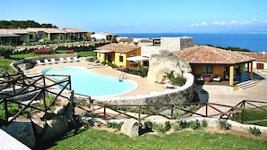 Un complexe hôtelier doté d’une piscine, de plusieurs bâtiments aux toits de tuiles et offrant une vue sur la mer.