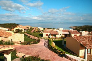A coastal village with terracotta-roofed buildings, a paved pathway, and a view of the sea. - Holiday Residence Punta Falcone Near Beach (Santa Teresa di Gallura)