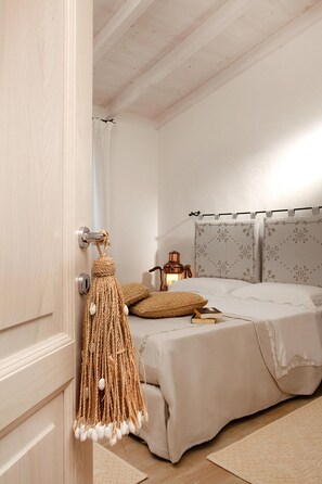 A bedroom with a bed, a hanging macrame keychain, a lamp, and patterned curtains. - Holiday Residence Punta Falcone Near Beach (Santa Teresa di Gallura)
