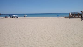 Uma praia com alguns guarda-sóis e pessoas.