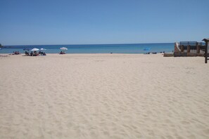 A beach with a few umbrellas and people. - Apartment in a Seaside Resort (Domus de Maria)