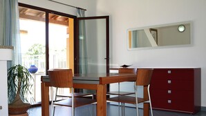 Ein moderner Essbereich mit einem Glastisch, vier Holzsesseln und einem roten Schrank.