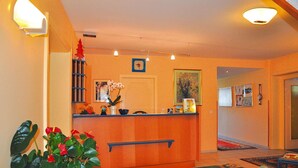 A reception area with a wooden counter, a potted plant, and a framed picture on the wall. - Flats Birkenhof, Dobriach Millstatter See (Radenthein)