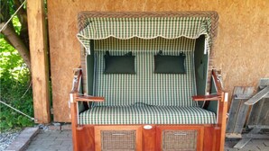 Een houten schommelzitplaats met een geruit dak, rieten zijpanelen en een metalen frame.