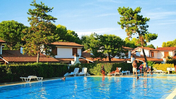 A swimming pool area with lounge chairs and a clear view of the surrounding buildings. - Apartment in Italy Near Sandy Beach (San Michele al Tagliamento)