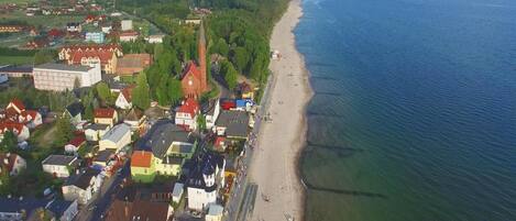An aerial view of a coastal town with a beach, houses, and a church.