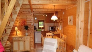 A cozy cabin interior with a wooden staircase, a dining area with a table and chairs, a kitchen with a sink and appliances, and a living room with a sofa. - Holiday House in Sarbinowo Near Baltic Beach (Mielno)