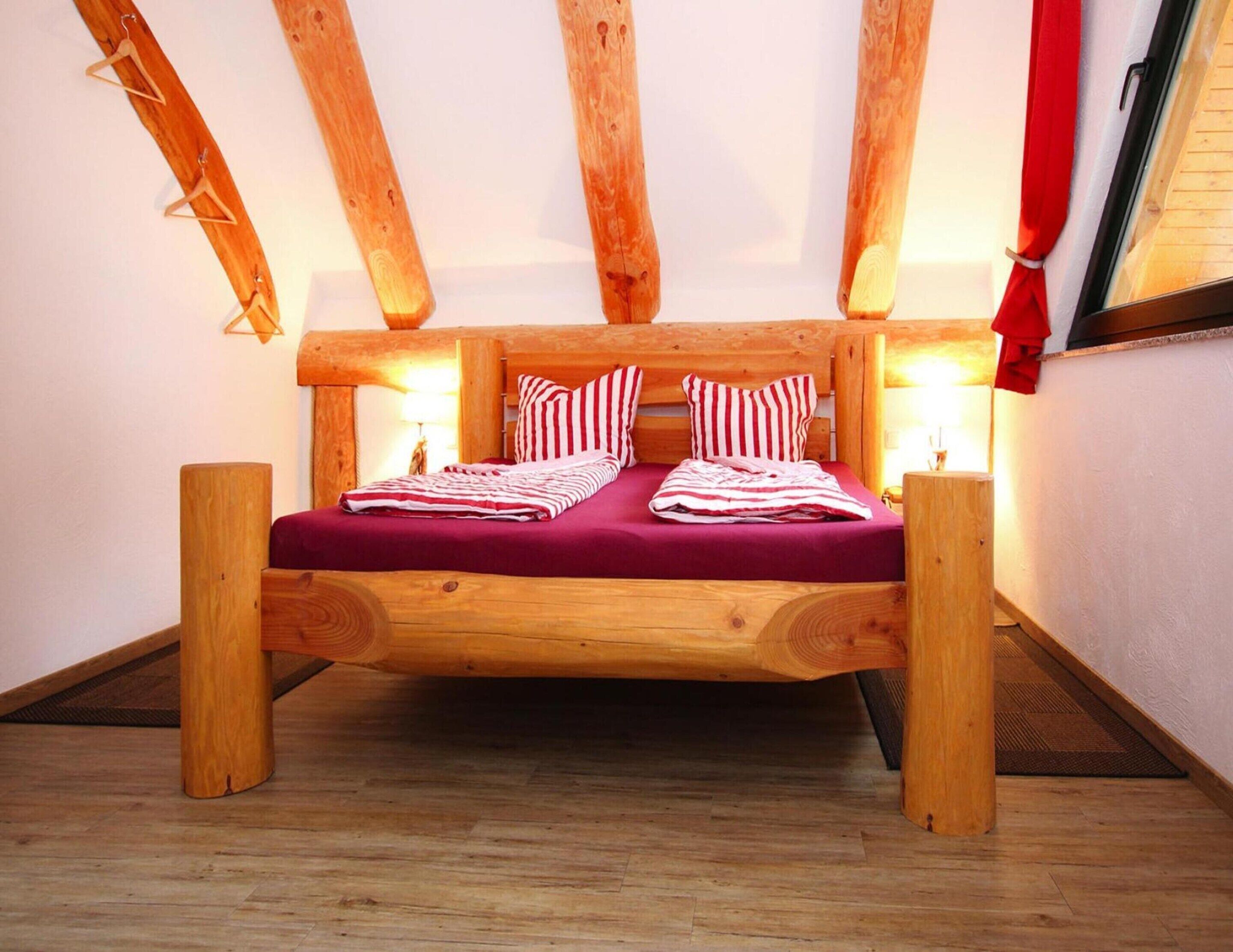 Un lit en bois avec une tête de lit, deux lampes de chevet et une couverture à rayures rouges et blanches.