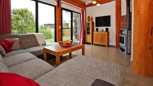 A cozy living room with a sofa, a coffee table, and a fireplace. - Ferienhaus Waldblick in Gohren-lebbin (Goehren-Lebbin)