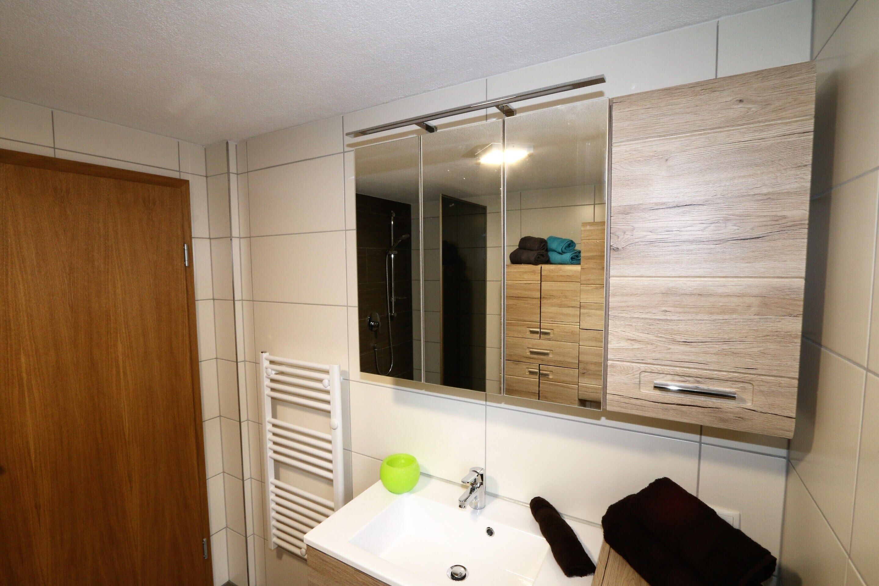 A bathroom with a wooden door, a white sink, a mirror, and a towel rack.