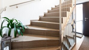 Un escalier avec des marches en bois et des rampes en métal, menant à une porte sombre.
